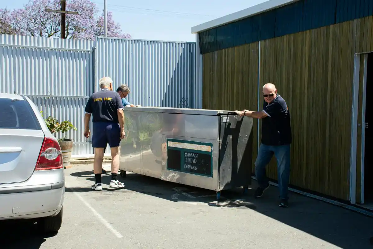 A team of three workers moving a large skip bin into position for installation as part of cheapest skip bins townsville service